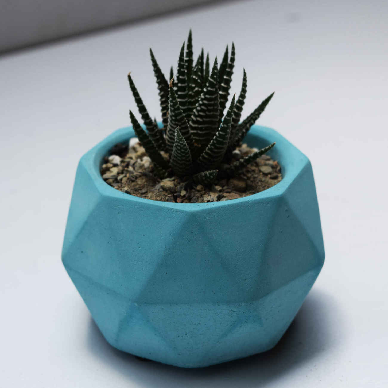 Minimalistische betonnen vaas met een veelvlakkige vorm in blauw, handgemaakt voor een eigentijds-geometrische uitstraling